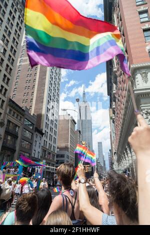 États-Unis, New York, NY - les participants brandient des drapeaux arc-en-ciel pendant que le New York City LGBTQ Pride March descend la Cinquième Avenue à Manhattan. Banque D'Images