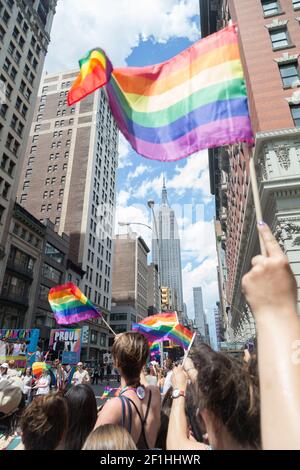 États-Unis, New York, NY - les participants brandient des drapeaux arc-en-ciel pendant que le New York City LGBTQ Pride March descend la Cinquième Avenue à Manhattan. Banque D'Images
