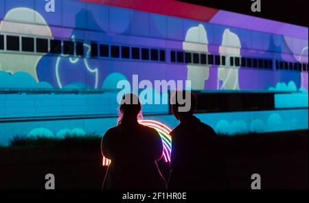 Canberra. 8 mars 2021. La photo prise le 8 mars 2021 montre des gens appréciant les lumières colorées pendant le festival Enlighten à Canberra, en Australie. Le festival annuel Enlighten se déroule du 26 février au 8 mars à Canberra, avec des bâtiments emblématiques éclairés par des lumières colorées. Credit: Liu Changchang/Xinhua/Alamy Live News Banque D'Images