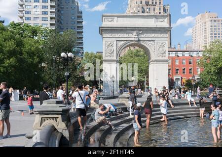 États-Unis, New York City, NY - les gens se frayent dans la fontaine de Washington Square dans le parc Washington Sqaure, en face de Washington Square Arch Banque D'Images