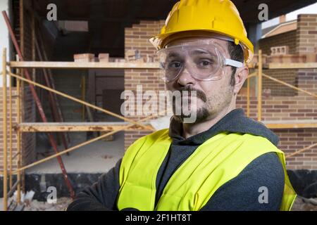 Faites-le vous-même ingénieur, homme habillé en jaune builder Casque avec lunettes de protection prêt à commencer les travaux de construction Banque D'Images