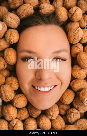 Femme souriante sur fond de noix. Manger des noix. Dents solides Banque D'Images