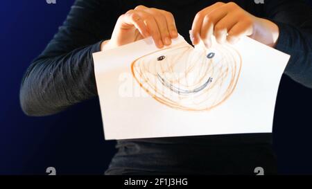 Une adolescente tient un panneau en papier dans sa main avec un sourire tiré au-dessus, le déchire et lui montre u Banque D'Images