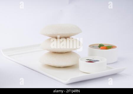 Didy ou IDLI, petit déjeuner indien du sud qui est magnifiquement disposé sur base rectangulaire blanche avec deux petits bols de sambar et chutney sur wh Banque D'Images