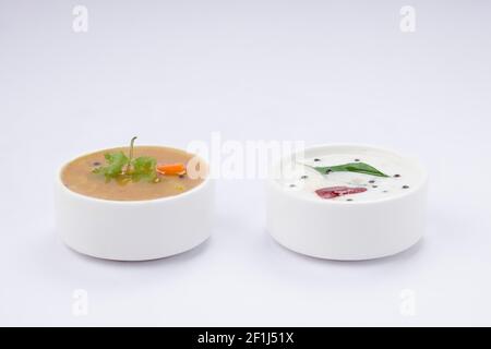 Chutney blanc noix de coco et sambar, disposés dans une table blanche qui est placée sur fond blanc texturé. Banque D'Images