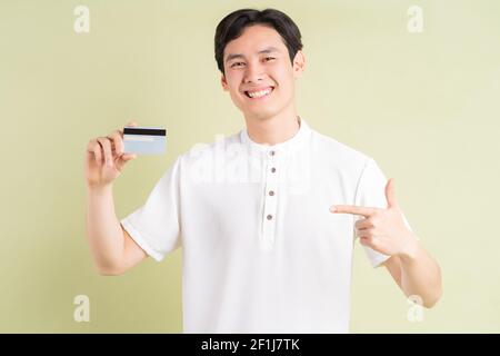 Beau homme d'affaires asiatique souriant et pointant du doigt sur le crédit carte Banque D'Images