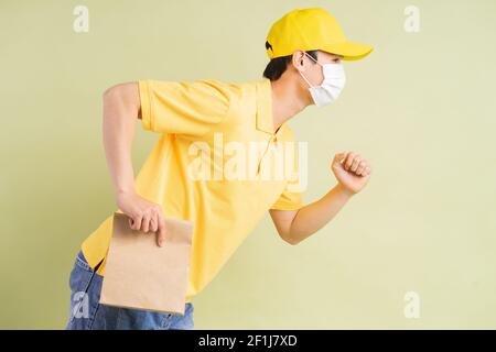 Un liveur asiatique tient le sac en papier avec lui et courir pour livrer les marchandises Banque D'Images