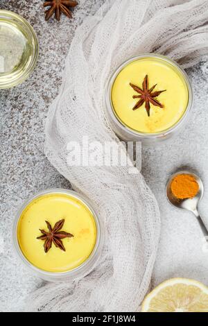 Curcuma, lait doré avec citron, cuillère avec poudre de curcuma, miel et textile sur fond gris. Concept de médecine alternative. Banque D'Images
