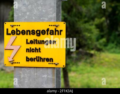 Panneau d'avertissement jaune avec texte allemand indiquant danger haute tension ne touchez pas les câbles Banque D'Images