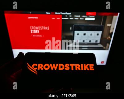 Personne tenant un téléphone portable avec le logo d'affaires de la société américaine de logiciels CrowdStrike Holdings Inc. À l'écran devant la page Web. Mise au point sur l'affichage du téléphone. Banque D'Images