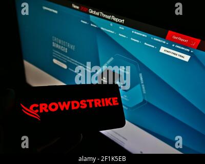 Personne détenant un smartphone avec le logo de la société de logiciels américaine CrowdStrike Holdings Inc. À l'écran devant le site Web. Mise au point sur l'affichage du téléphone. Banque D'Images
