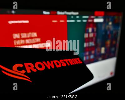 Téléphone mobile avec le logo de la société américaine de cybersécurité CrowdStrike Holdings Inc. À l'écran devant la page Web. Mise au point au centre-gauche de l'écran du téléphone. Banque D'Images
