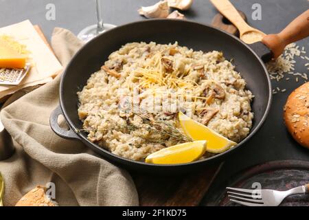 Poêle à frire avec un savoureux risotto sur fond sombre Banque D'Images