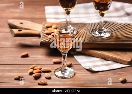 Composition avec verres de liqueur d'amande et noix sur bois arrière-plan Banque D'Images