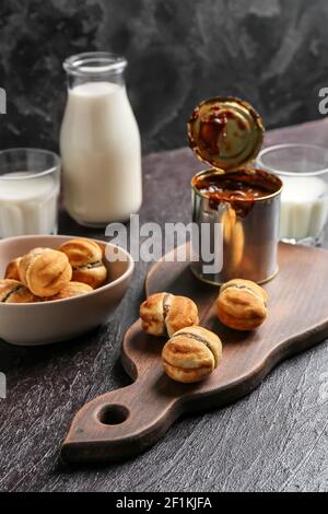 Biscuits savoureux et boîte de lait concentré bouilli arrière-plan sombre Banque D'Images