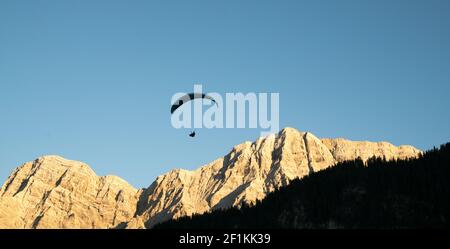 Silhouette de parapente dans le paysage de montagne des Dolomites dans la lumière du soir Banque D'Images
