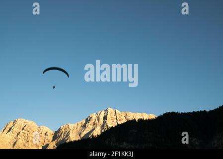 Silhouette de parapente dans le paysage de montagne des Dolomites dans la lumière du soir Banque D'Images