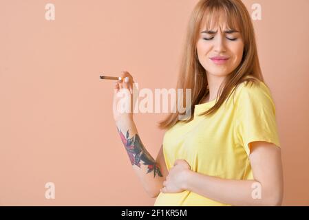 Femme enceinte dégoûtée avec une cigarette sur fond de couleur. Concept de refus de mauvaise habitude Banque D'Images