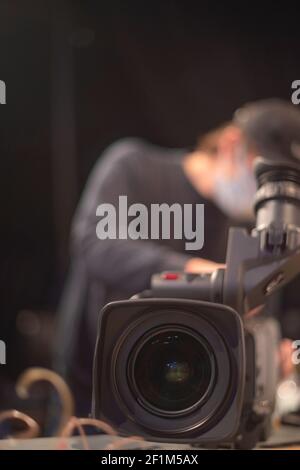 un caméraman masqué filme un spectacle télévisuel en studio. TÉLÉVISION Banque D'Images