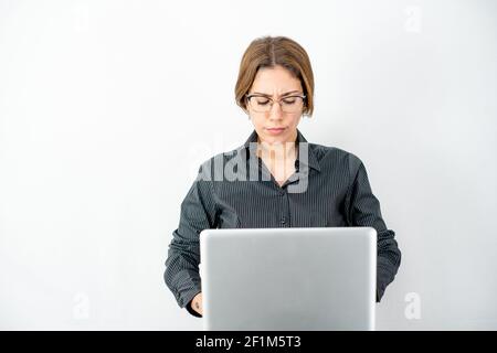 Femme d'affaires avec chemise sombre et verres concentrés sur l'ordinateur le travail regarde l'écran portant des vêtements de travail isolés espace de copie verso blanc Banque D'Images
