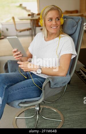 Femme assise dans un fauteuil et utilisant une tablette numérique Banque D'Images