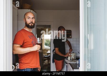 Homme tenant des lunettes de vin dans la cuisine Banque D'Images