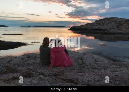 Femme en mer prenant une photo du coucher du soleil Banque D'Images