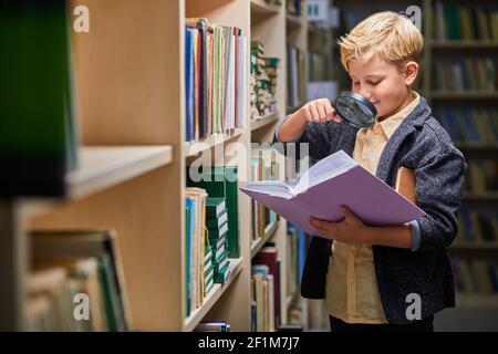 livre de lecture de garçon d'âge préscolaire dans la bibliothèque avec patience, le garçon d'enfant de race blanche se concentre sur l'éducation, l'obtention de connaissances. développement du cerveau de l'enfant, lea Banque D'Images