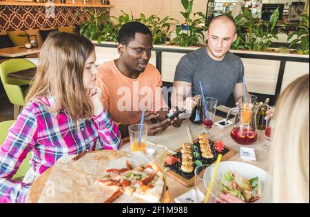 Une société multiculturelle de l'entreprise des jeunes dans un café de manger, de boire des boissons sushi rolls s'amusant Banque D'Images