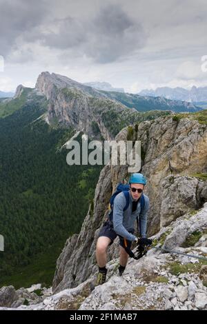 Homme dans ses années vingt grimpant une raide via Ferrata dedans Les Dolomites d'Alta Badia Banque D'Images