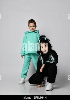 Deux amis enfants, garçon et fille, se posent ensemble tenues de sport modernes et élégantes à capuche, pantalons et baskets Banque D'Images