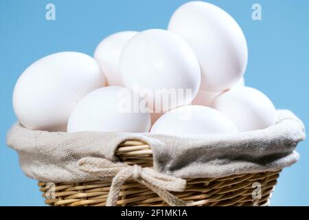 Oeufs de poulet dans un panier de paille, beaucoup d'oeufs blancs frais crus dans un récipient, produit naturel d'Eko, Pâques préparant CopySpace Banque D'Images