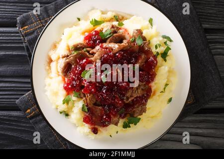 Authentique venaison de Poronkaristys servie avec des pommes de terre et une sauce aux baies de lingonyre dans une assiette sur la table. Vue horizontale dessus Banque D'Images