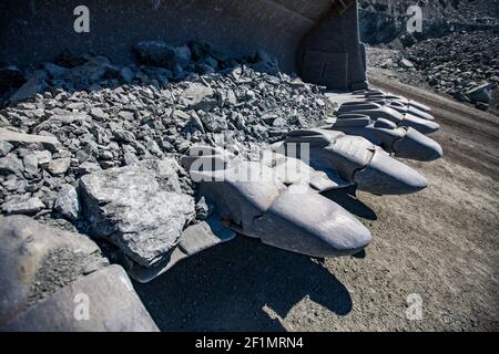 Gros plan des dents en acier du godet de bulldozer. Carrière et route en arrière-plan. Banque D'Images