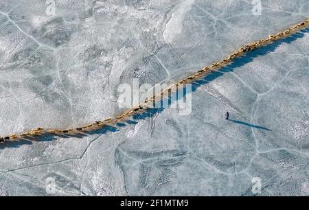 (210309) -- LHASSA, le 9 mars 2021 (Xinhua) -- une photo aérienne prise le 6 mars 2021 montre un troupeau de moutons marchant le long d'un chemin sûr sur le lac gelé Puma Yumco pendant leur migration annuelle dans la région autonome du Tibet du sud-ouest de la Chine. Chaque année, au plus froid, au village de Dowa, à 5,070 mètres au-dessus du niveau de la mer, des milliers de moutons traversent l'eau gelée jusqu'aux îles du lac Puma Yumco, l'un des plus hauts lacs du monde. Les bergers passent généralement un mois avec les animaux sur les îles, où l'herbe pousse à la taille. Lorsque le printemps approche, les troupeaux de moutons seront ramenés à leur for Banque D'Images