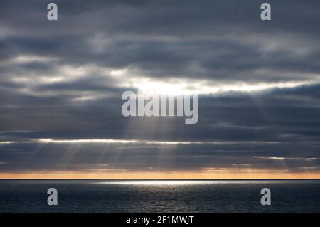 Le soleil se brise à travers les nuages orageux au-dessus de la mer au large de Cornwall, au Royaume-Uni Banque D'Images