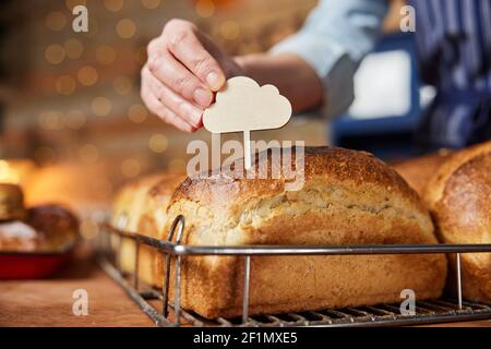 Assistant-revendeur de la boulangerie/pâtisserie mettant une étiquette vierge dans les aliments fraîchement cuits Pains de pain Sourdough cuits Banque D'Images