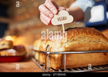 Assistant-revendeur de la boulangerie mettant l'étiquette de Vega dans des produits fraîchement cuits Pains de pain Sourdough cuits Banque D'Images