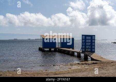 Une promenade en bois menant à une cabine de pêche bleue sur l'océan Banque D'Images