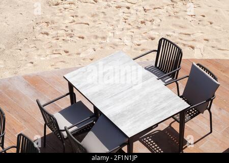 Des chaises et une table vide sont sur une terrasse de plage une journée ensoleillée Banque D'Images