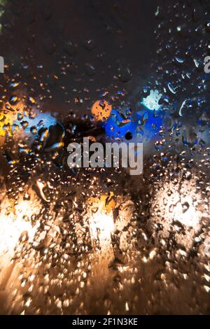 Gouttes sur le verre embué. Lumières floues de la ville du soir. La mise au point se fait sur le verre. Banque D'Images