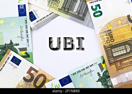 Photo TopView sur le thème du revenu de base universel. L'abréviation UBI sur papier, entourée de billets en euros Banque D'Images