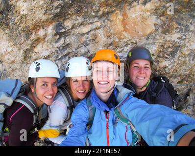 Quatre femmes grimpantes célèbrent le sommet de la montagne en prenant une photo de groupe Banque D'Images