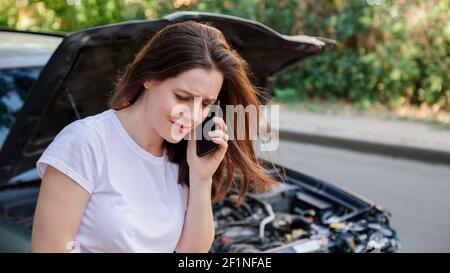 Femme effrayée dans le stress après l'accident de voiture appel à l'assurance auto pour l'aide. Conducteur pleurant devant une voiture de naufrage dans un accident de voiture. roa dangereux Banque D'Images