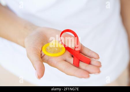 Femme d'affaires attirante avec ruban rouge et condom montrant dans les mains Banque D'Images