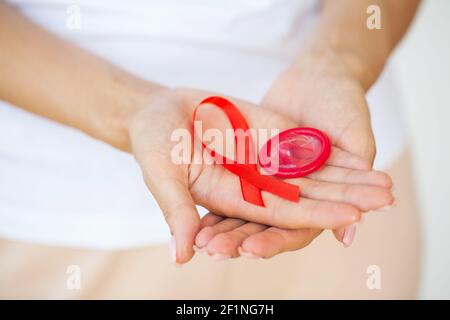 Femme d'affaires attirante avec ruban rouge et condom montrant dans les mains Banque D'Images