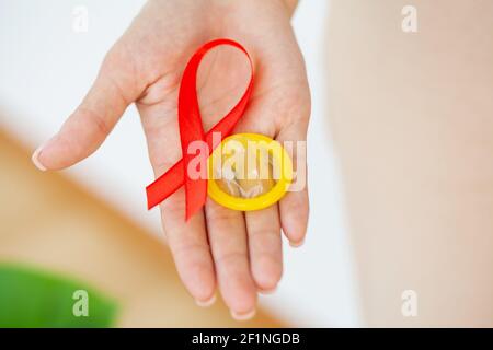 Femme d'affaires attirante avec ruban rouge et condom montrant dans les mains Banque D'Images