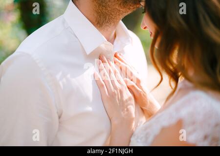 Le marié embrasse doucement la mariée sur le front, la mariée met ses mains sur la poitrine du marié Banque D'Images