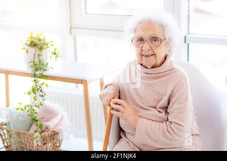Bonne vieille femme assise dans un intérieur lumineux Banque D'Images
