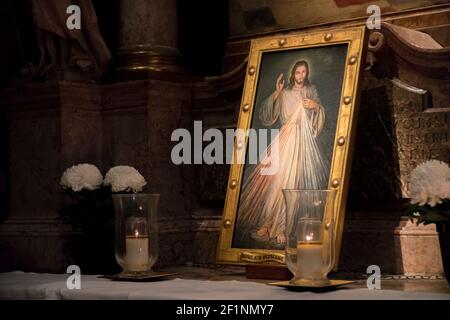 Vienne, Autriche, 10.31.2019. Dans une église un sanctuaire avec une image encadrée d'or de Jésus-Christ. Bougie lumière et fleurs blanches Banque D'Images